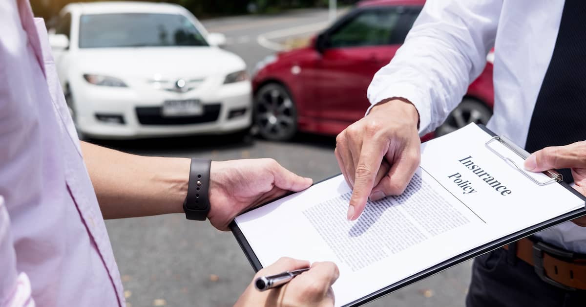 driver and insurance adjuster reviewing policy after a car accident