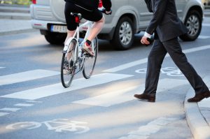 Pedestrian crossing in crosswalk with bicyclist in front of them