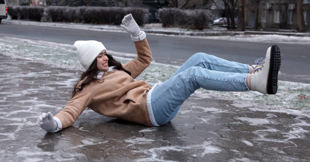 young woman slipping and falling on icy sidewalk