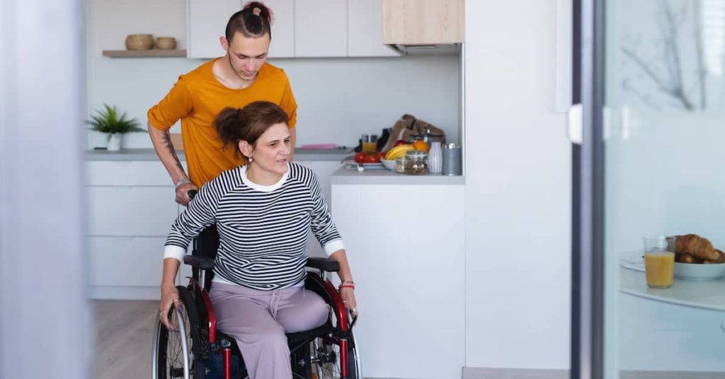 young man pushing a woman with an above-the-knee amputation in a wheelchair 