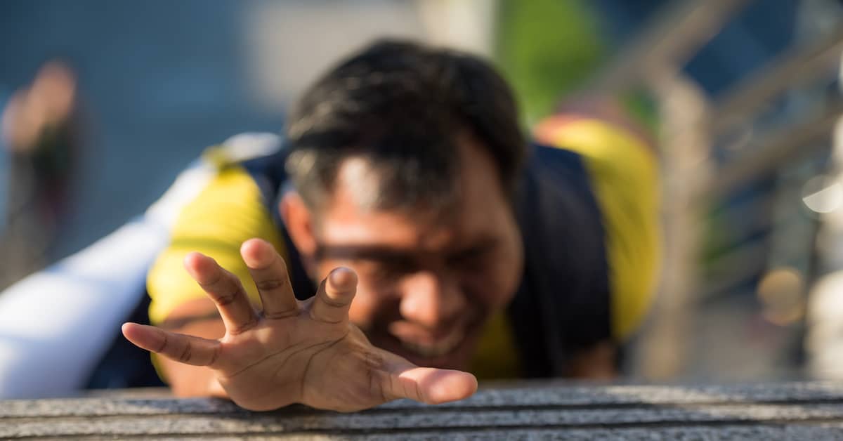 man lying on the ground extending his hand outward after a slip and fall