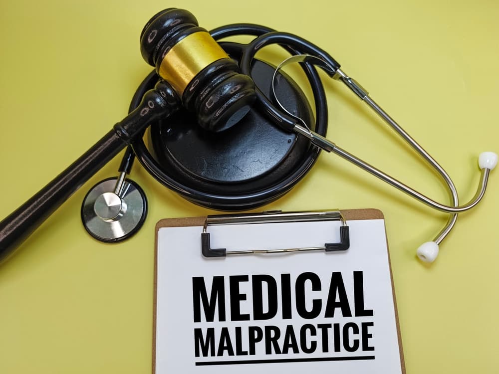 Clipboard labeled "Medical Malpractice" alongside a judge’s gavel and stethoscope, symbolizing healthcare negligence, legal claims, patient rights, and doctor liability.