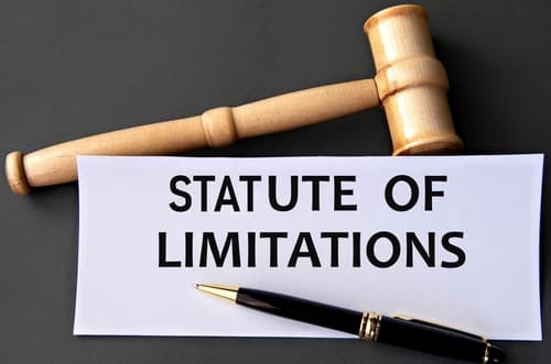Statute of Limitations: Text displayed on a dark background with a judge's gavel, written on white paper.