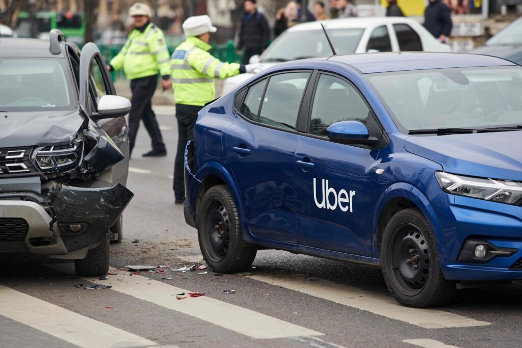 Uber car accident with another vehicle on city street, police officers investigating crash scene. Uber car accident with another vehicle on city street, police officers investigating crash scene.