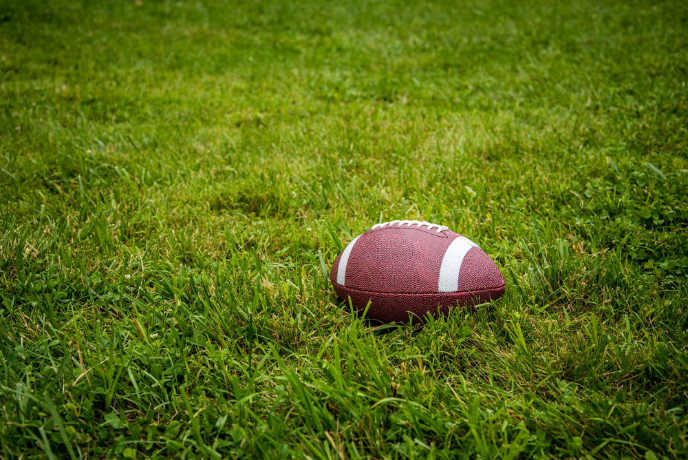 A football resting on a grassy field, symbolizing game days that can increase the risks of DUI accidents when alcohol is involved.
