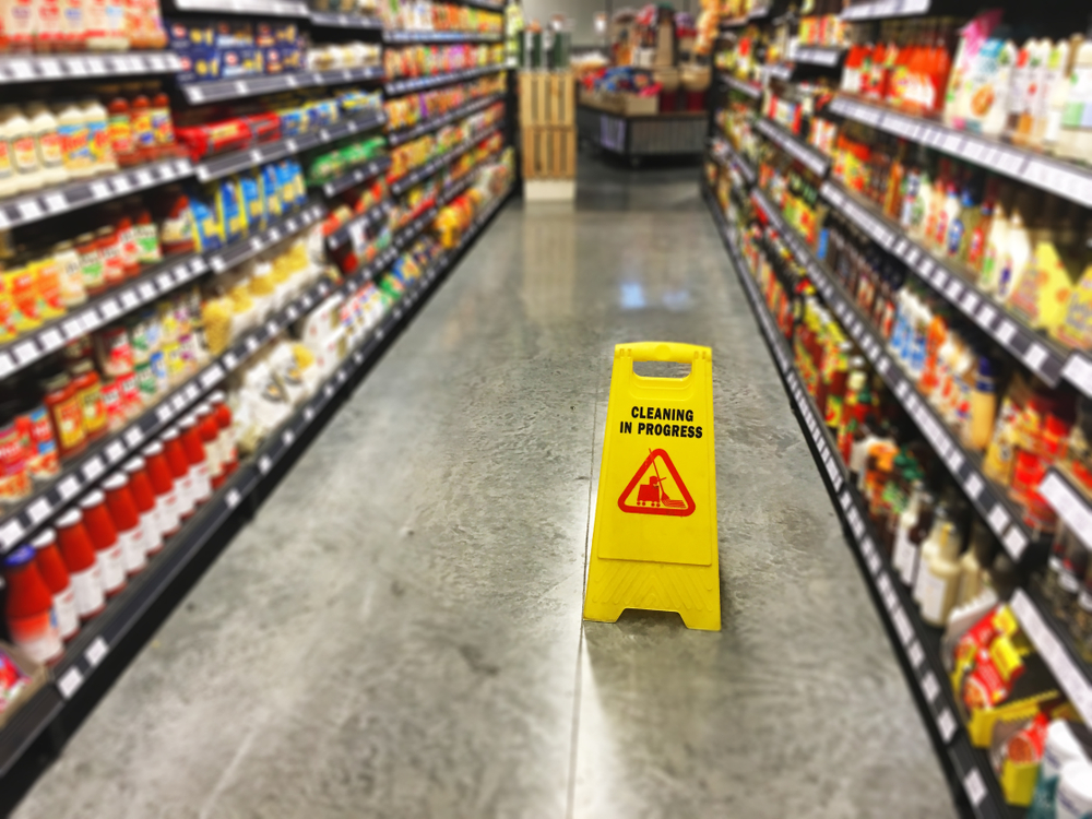 Connecticut slip and fall accident lawyer hazard sign on wet grocery store floor aisle.