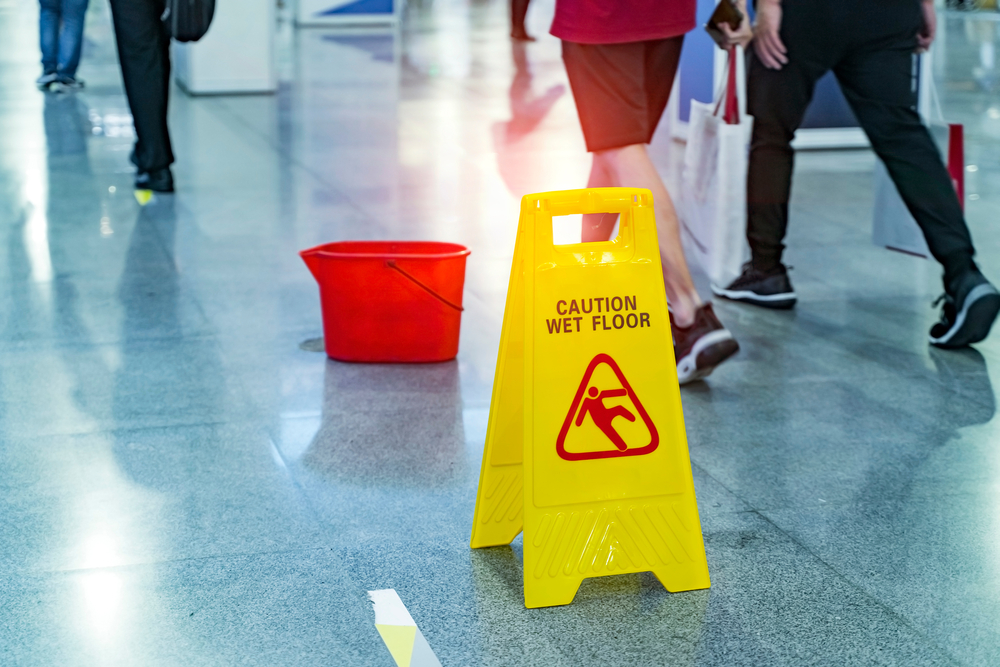 Wet floor sign and cleaning bucket in mall walkway showing hazard related to Danbury slip and fall lawyers help after Danbury Fair Mall accidents