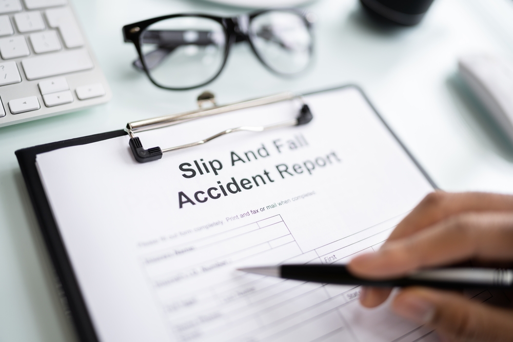 Person filling out slip and fall accident report form at desk related to Danbury slip and fall lawyers
