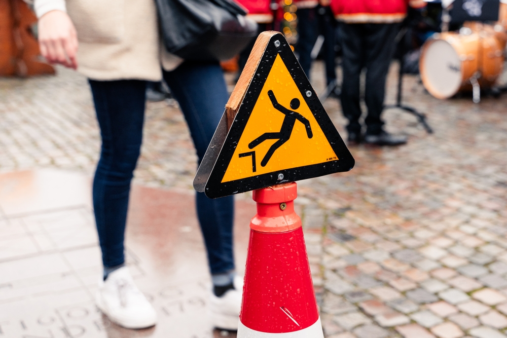Warning sign for slippery surface on sidewalk highlighting danger relevant to Danbury slip and fall lawyer.