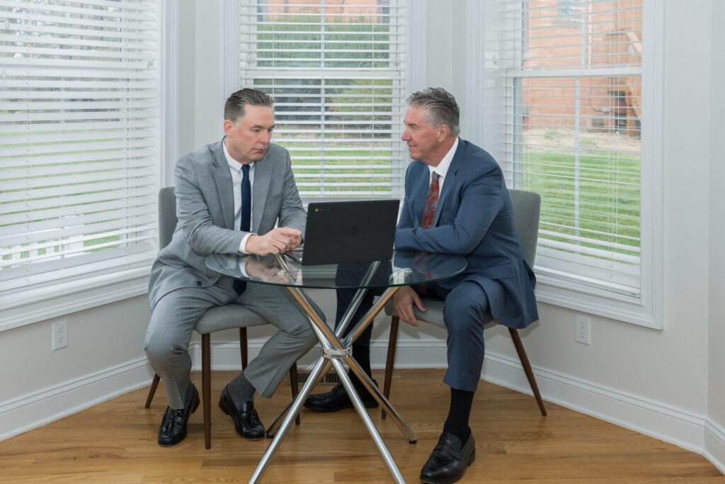 Brian and Chris Flood look at a laptop together, discussing a case.
