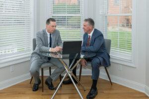 Brian and Chris Flood look at a laptop together, discussing a case.