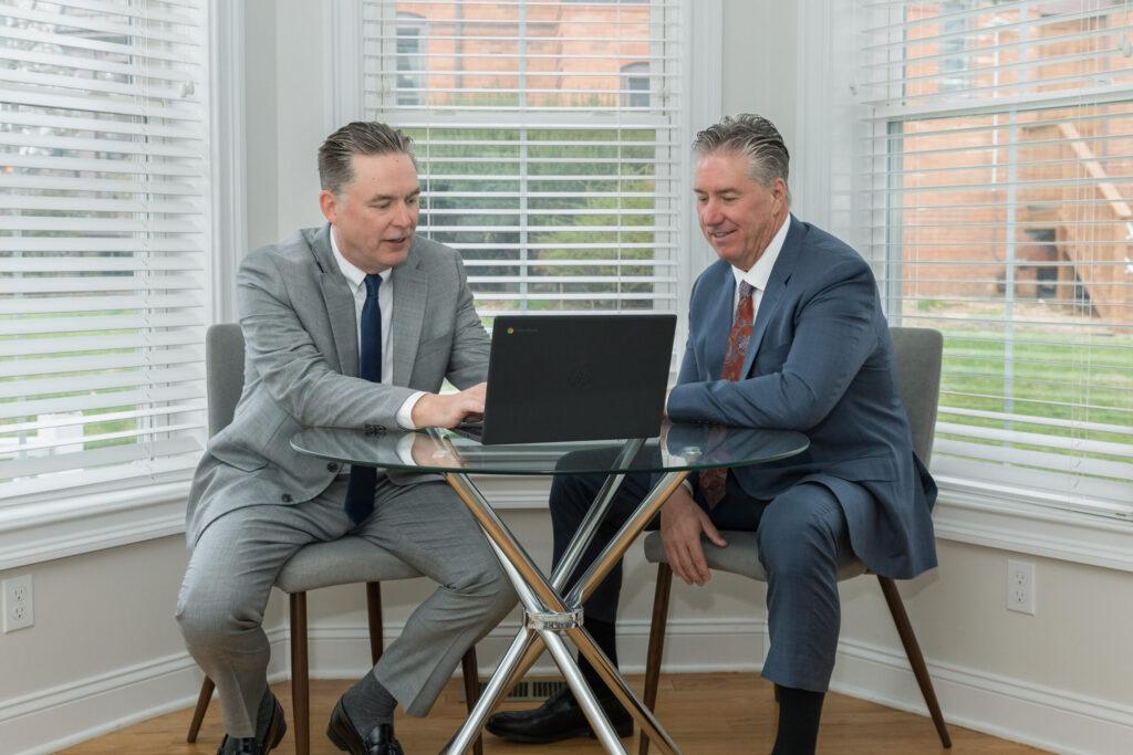 Attorneys Brian and Chris Flood discuss a case over a laptop
