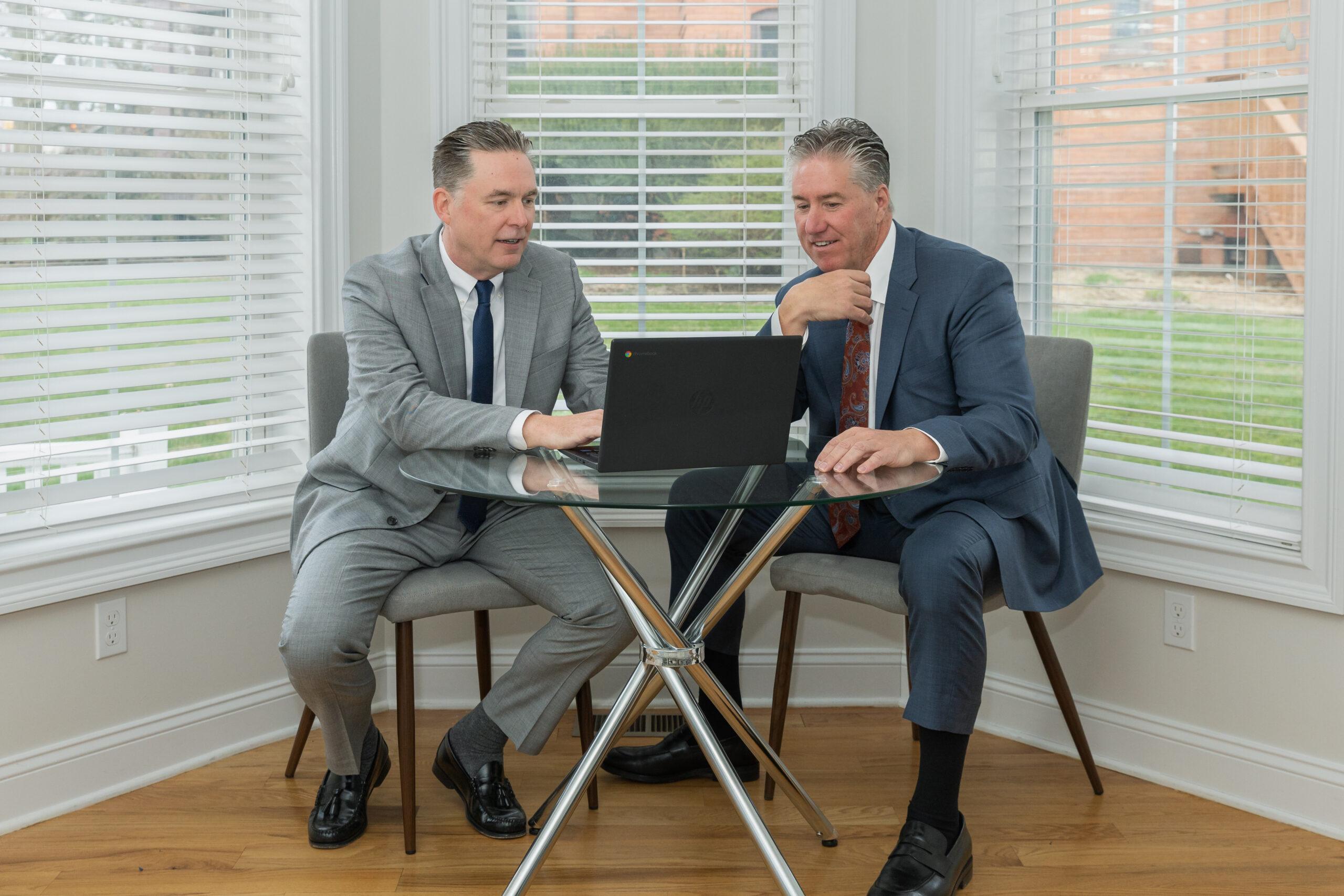 Attorneys Brian and Chris Flood discuss a case over a laptop