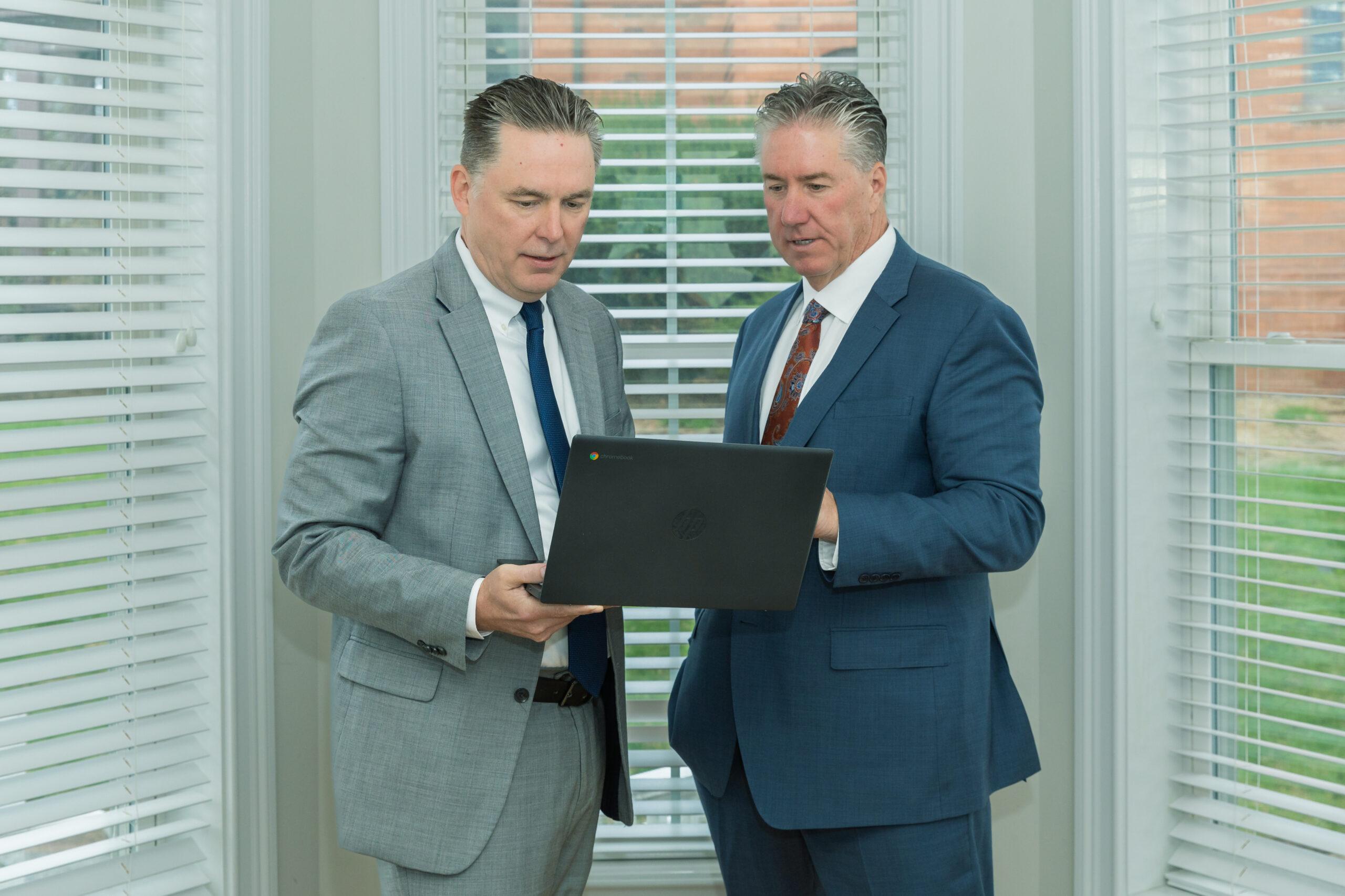 Attorneys Brian and Chris Flood discuss a case over a laptop