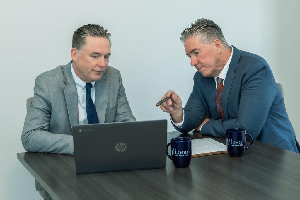 Attorneys Brian and Chris Flood discuss a case on a laptop
