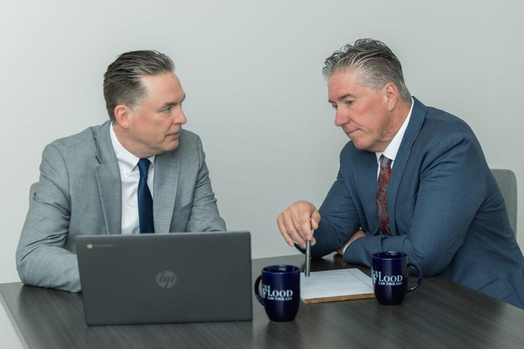 Attorneys Brian and Chris Flood discuss a case on a laptop