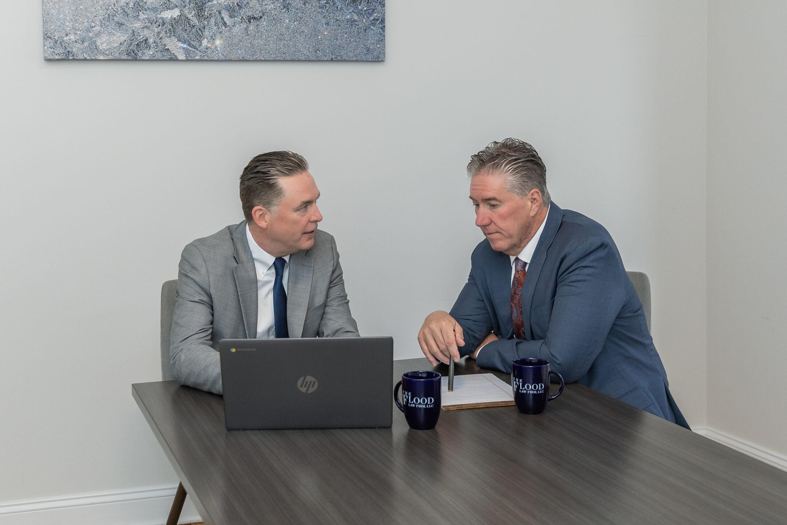 Attorneys Brian and Chris Flood discuss a case over a laptop