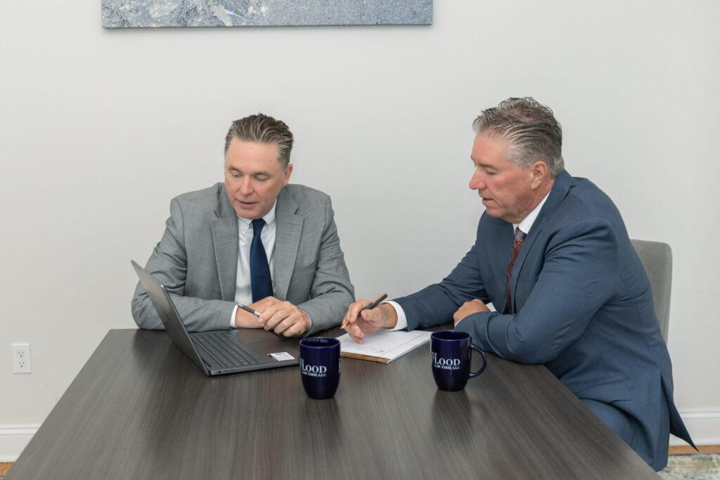 Attorneys Brian and Chris Flood discuss a case over a laptop
