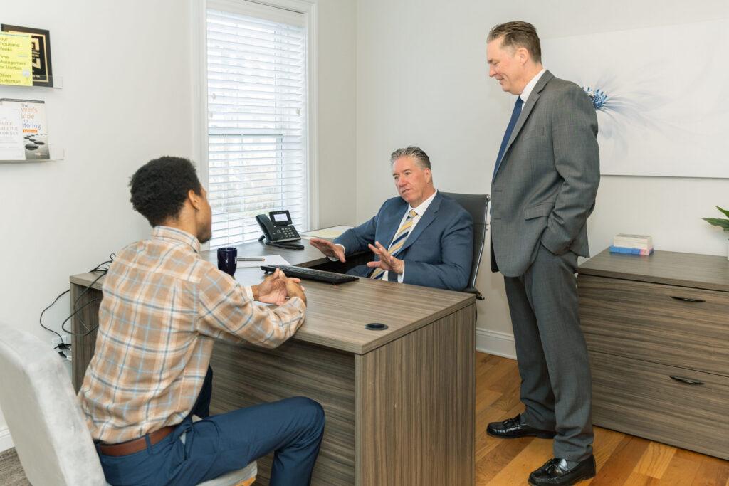 Brian and Chris Flood speak with a client in office