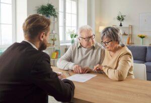 An older couple reviews a contract across a desk with a lawyer