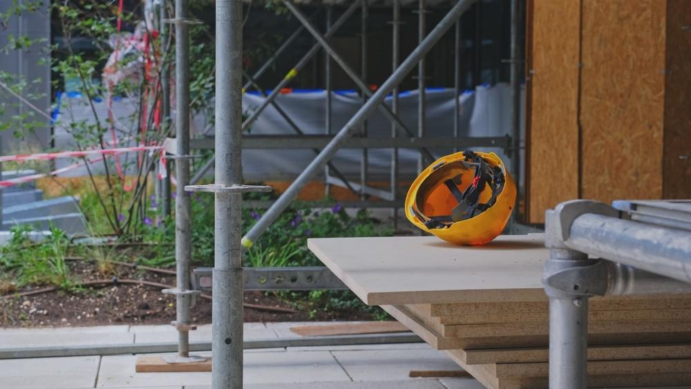 Stylized image of a hard hat on a bench beneath scaffolding