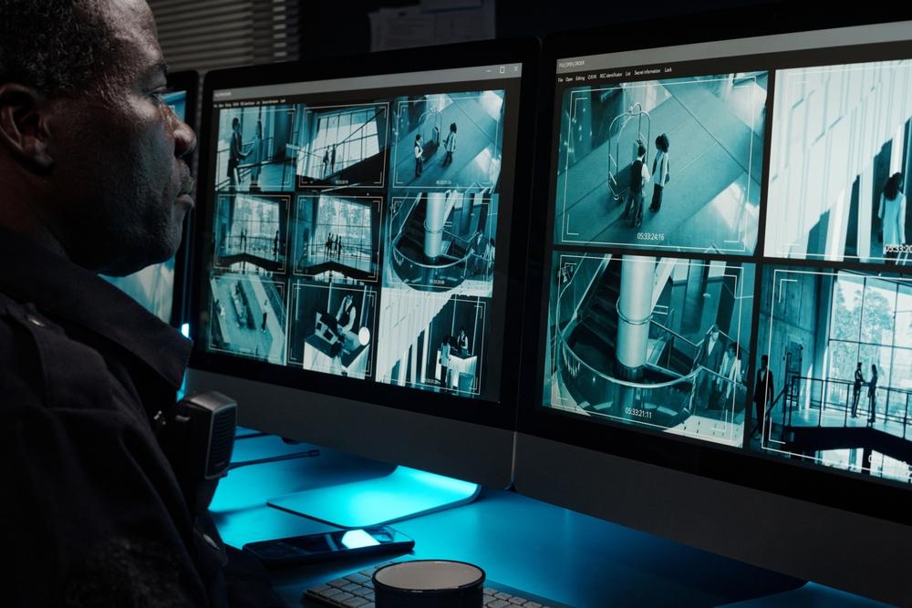 Security guard monitors cameras on dual screens